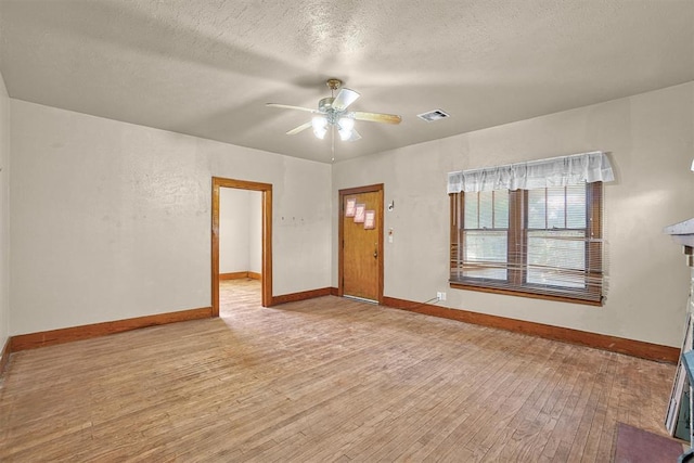 interior space with light wood-style floors, a textured ceiling, a ceiling fan, baseboards, and visible vents