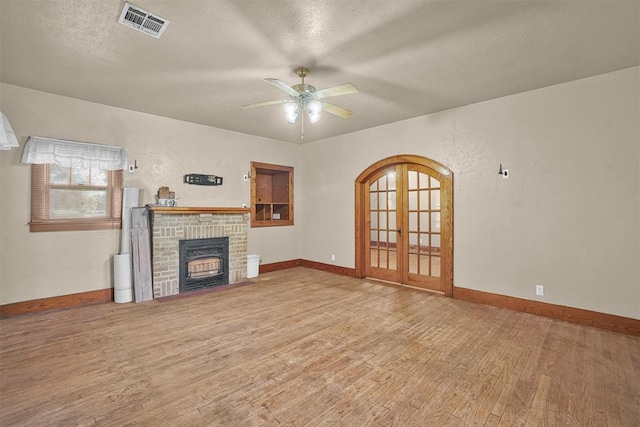 unfurnished living room featuring french doors, a ceiling fan, baseboards, wood finished floors, and visible vents