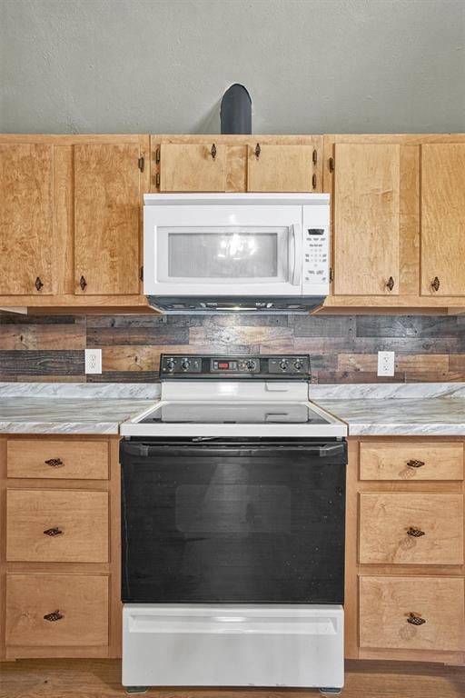 kitchen featuring light brown cabinets, white microwave, light countertops, electric range oven, and light wood-style flooring