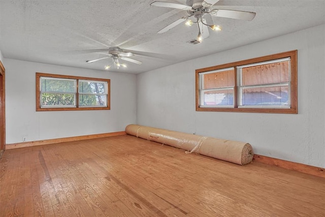 empty room featuring baseboards, a ceiling fan, hardwood / wood-style flooring, and a textured ceiling