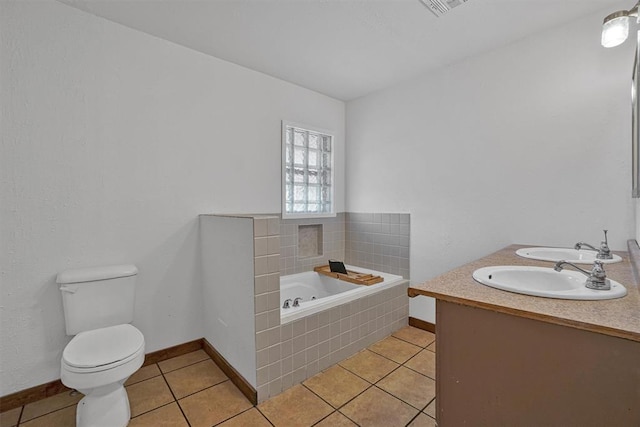 bathroom with a sink, tile patterned flooring, toilet, baseboards, and a garden tub