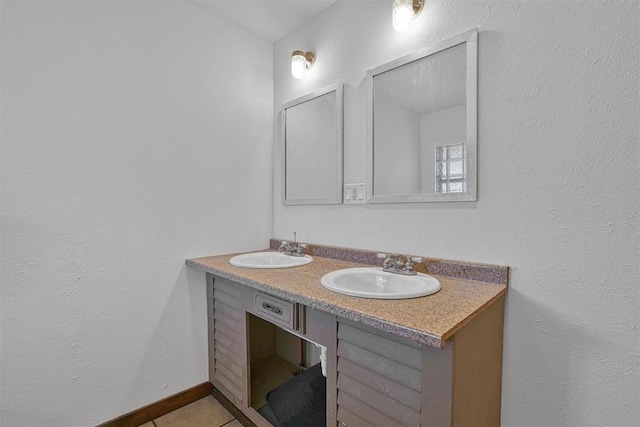bathroom featuring double vanity, a sink, baseboards, and tile patterned flooring