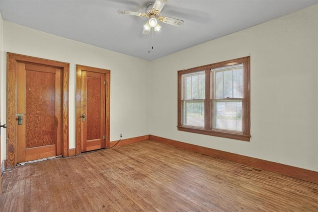 empty room featuring light wood-type flooring, a ceiling fan, and baseboards