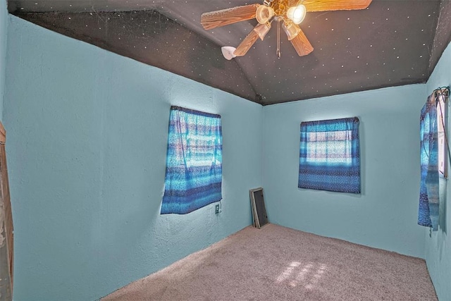 empty room with carpet floors, a textured wall, ceiling fan, and lofted ceiling
