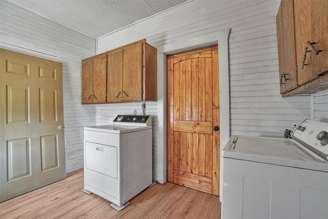 laundry area featuring cabinet space, separate washer and dryer, and wood walls