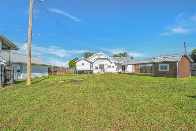 back of house with a lawn, fence, a storage shed, and an outdoor structure
