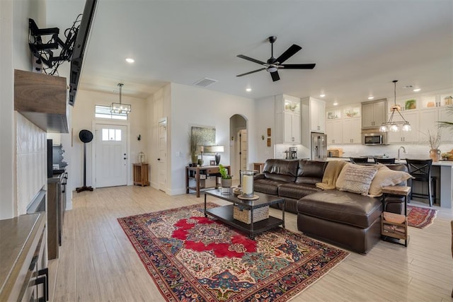 living area with a ceiling fan, visible vents, arched walkways, light wood-type flooring, and recessed lighting