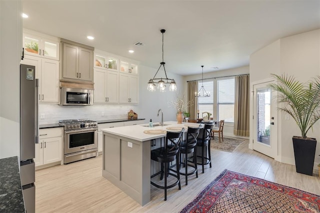 kitchen with decorative backsplash, a breakfast bar, a sink, light wood-style flooring, and stainless steel appliances