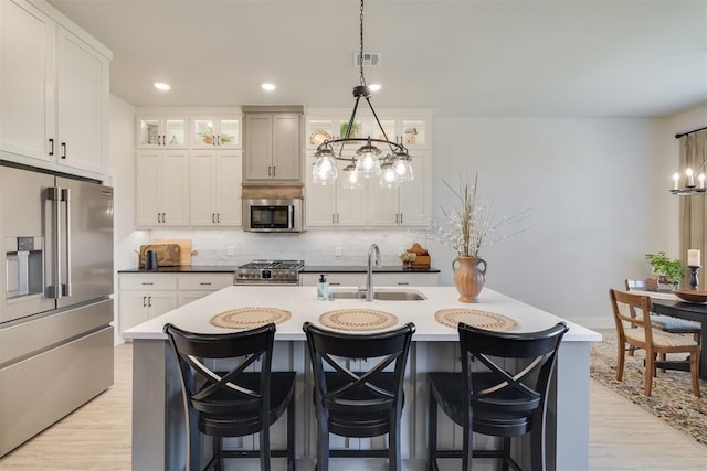 kitchen with visible vents, decorative backsplash, a center island with sink, a chandelier, and appliances with stainless steel finishes