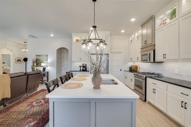 kitchen featuring an inviting chandelier, appliances with stainless steel finishes, tasteful backsplash, and arched walkways