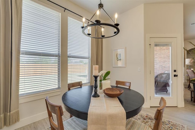 dining room featuring baseboards, light wood finished floors, and a chandelier