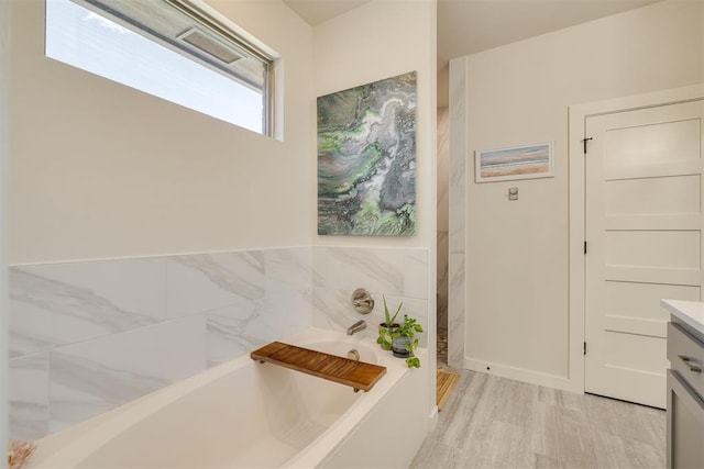 full bathroom featuring wood finished floors, a bath, and vanity