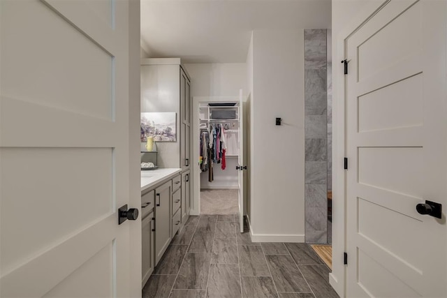 full bathroom with vanity, walk in shower, and a walk in closet