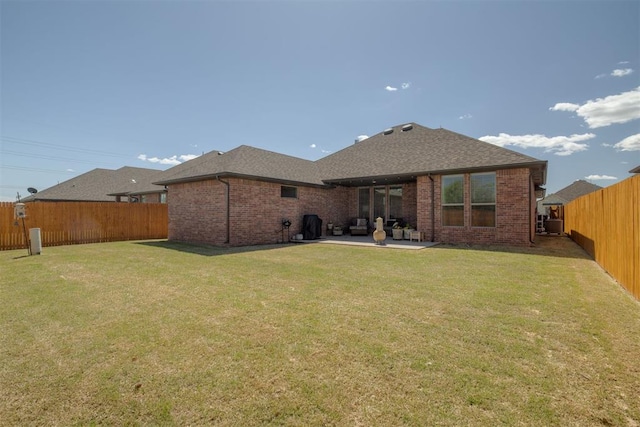 back of house featuring brick siding, a fenced backyard, a yard, and a patio