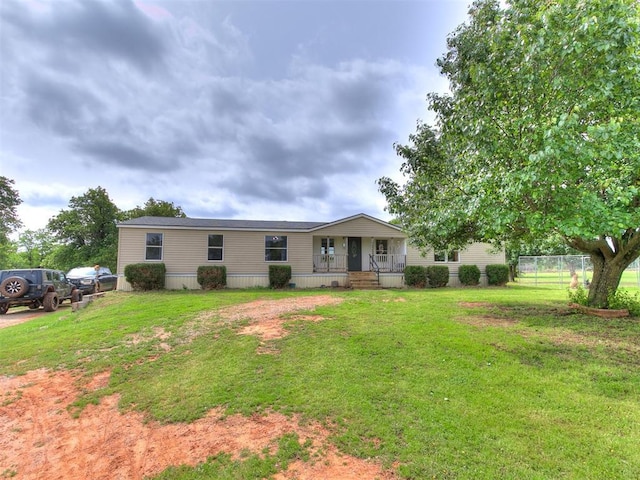 view of front of property featuring fence, covered porch, and a front yard