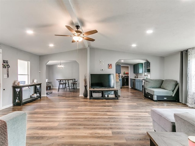 living area featuring arched walkways, ceiling fan, lofted ceiling with beams, and wood finished floors