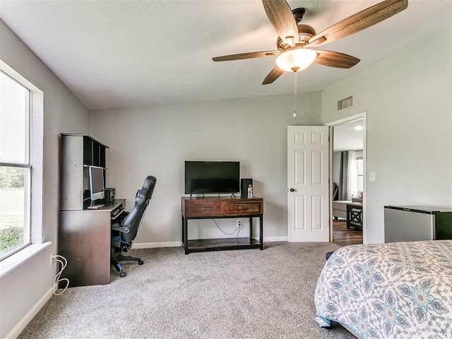 bedroom featuring carpet, freestanding refrigerator, a ceiling fan, baseboards, and visible vents
