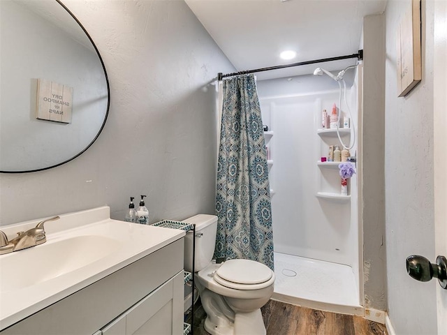 full bathroom featuring vanity, wood finished floors, toilet, and a shower stall