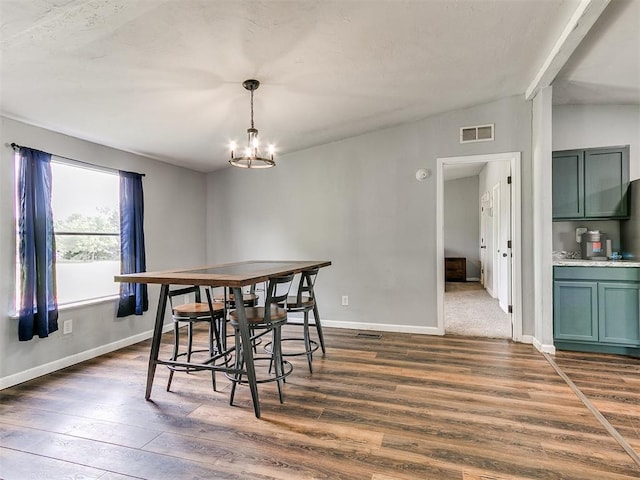 dining area with dark wood-style flooring, baseboards, visible vents, and a chandelier