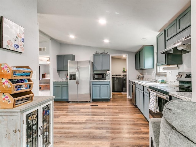kitchen featuring visible vents, light wood-type flooring, washer and clothes dryer, a sink, and stainless steel appliances