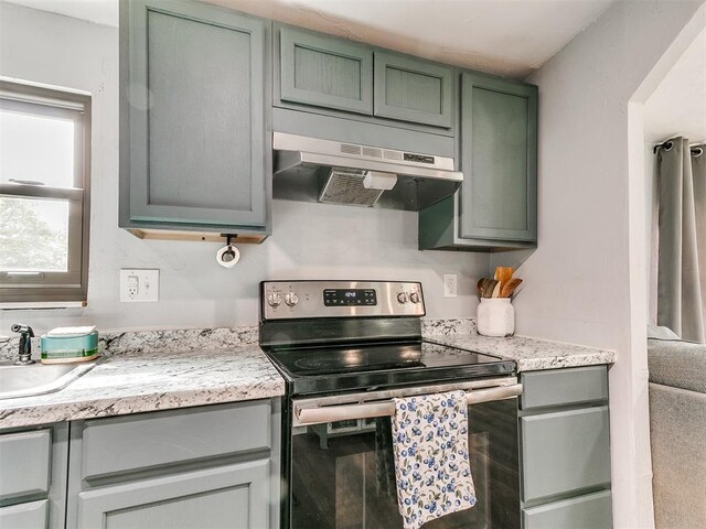 kitchen with under cabinet range hood, a sink, green cabinets, and stainless steel range with electric stovetop