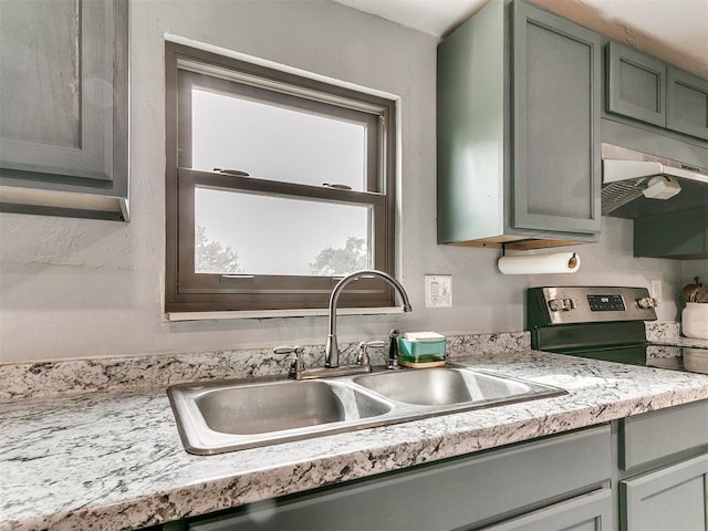 kitchen featuring light countertops, under cabinet range hood, a sink, and electric stove