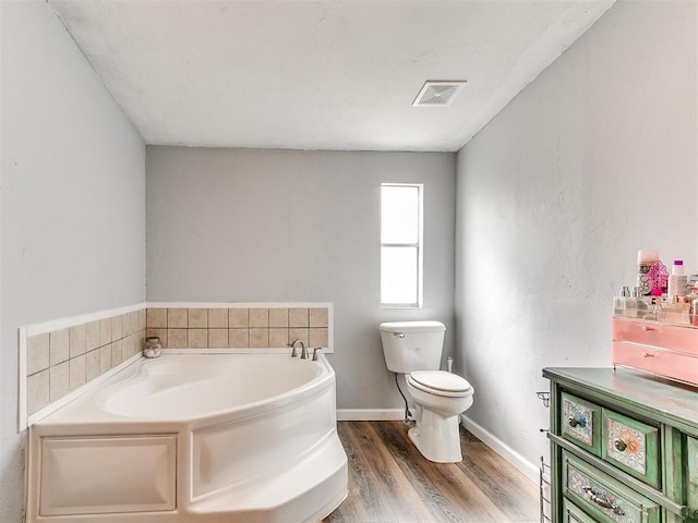full bath with a bath, visible vents, wood finished floors, baseboards, and toilet