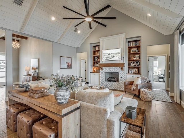 living area featuring wood-type flooring, visible vents, ceiling fan, high vaulted ceiling, and a tiled fireplace