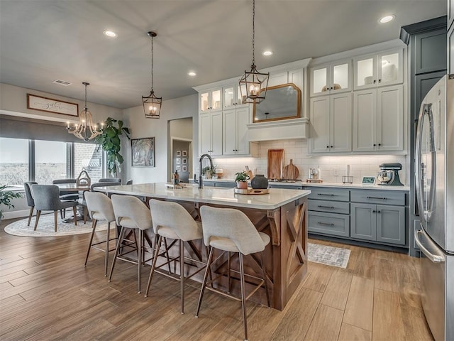 kitchen featuring freestanding refrigerator, a sink, wood finished floors, and light countertops