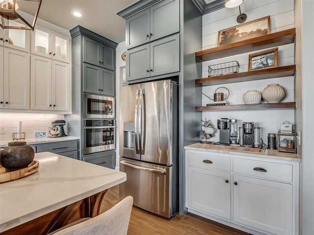 kitchen with light countertops, stainless steel appliances, recessed lighting, light wood-type flooring, and backsplash