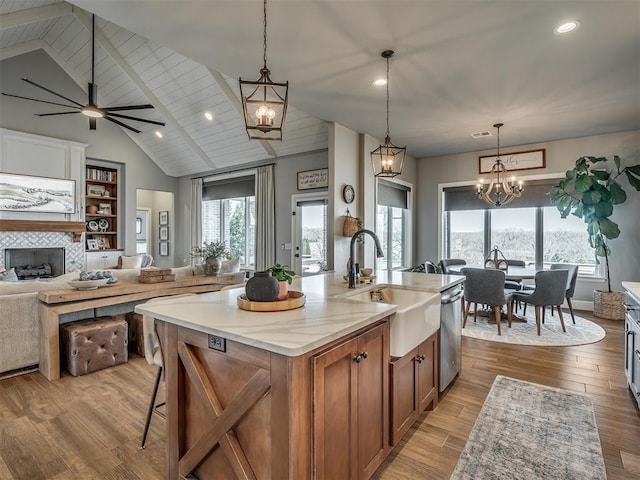 kitchen featuring stainless steel dishwasher, open floor plan, recessed lighting, brown cabinets, and a sink