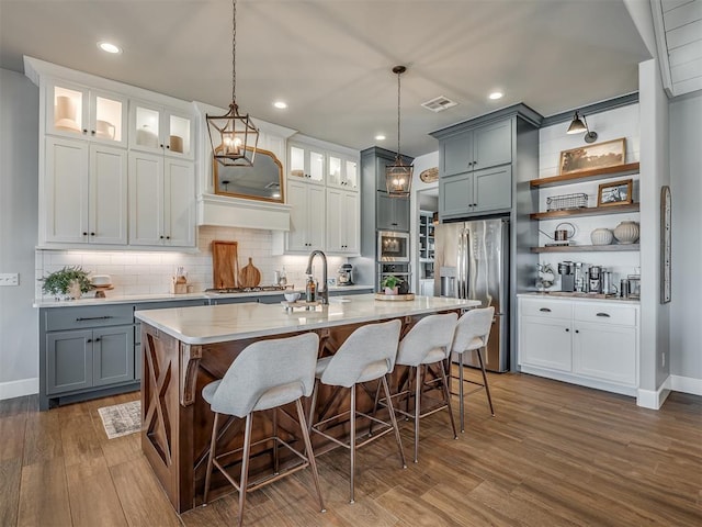 kitchen with visible vents, open shelves, dark wood-style flooring, light countertops, and stainless steel appliances