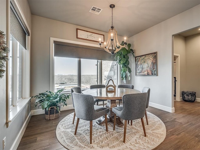 dining area featuring an inviting chandelier, a wealth of natural light, dark wood-type flooring, and visible vents