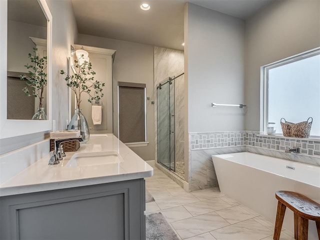 bathroom featuring a freestanding bath, a shower stall, a sink, marble finish floor, and recessed lighting