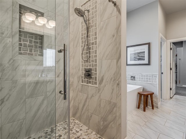 full bath with a freestanding tub, a shower stall, and tile walls