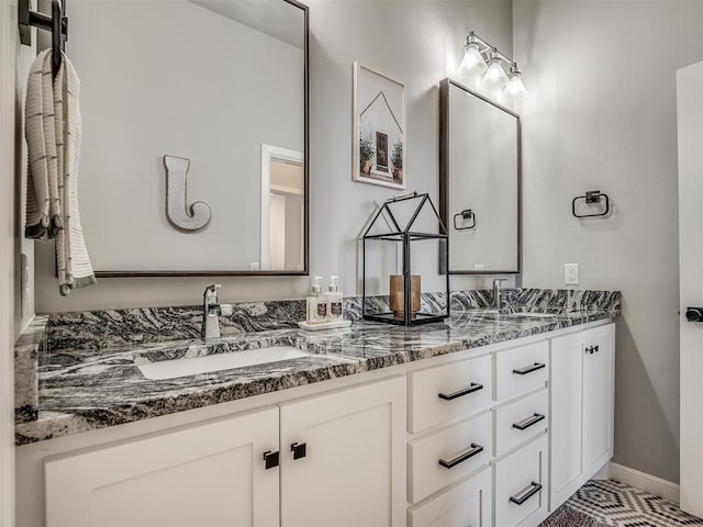 full bathroom with double vanity, a sink, and baseboards