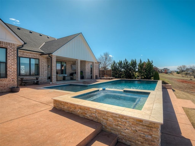 outdoor pool with an in ground hot tub and a patio area