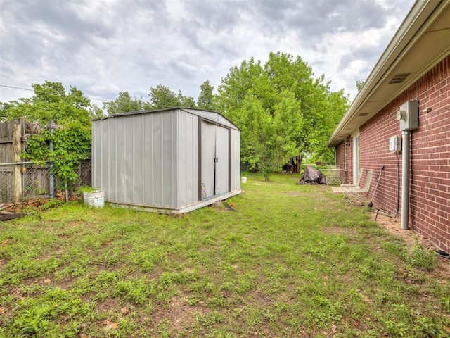 view of yard with fence, a storage unit, and an outbuilding