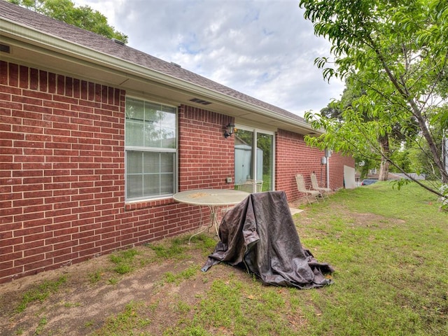 rear view of house with a lawn and brick siding