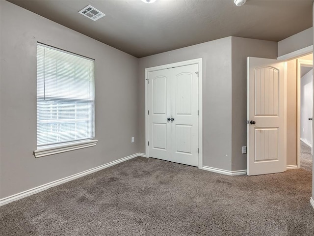 unfurnished bedroom with baseboards, visible vents, carpet, and a closet