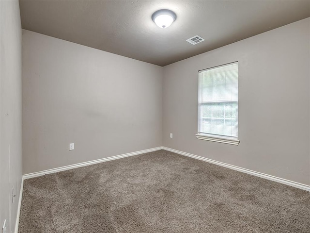 carpeted spare room featuring baseboards and visible vents