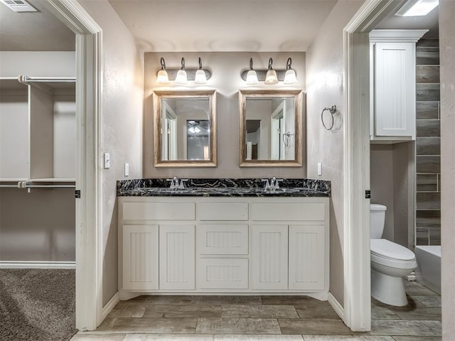 full bathroom with a sink, baseboards, toilet, and wood finished floors