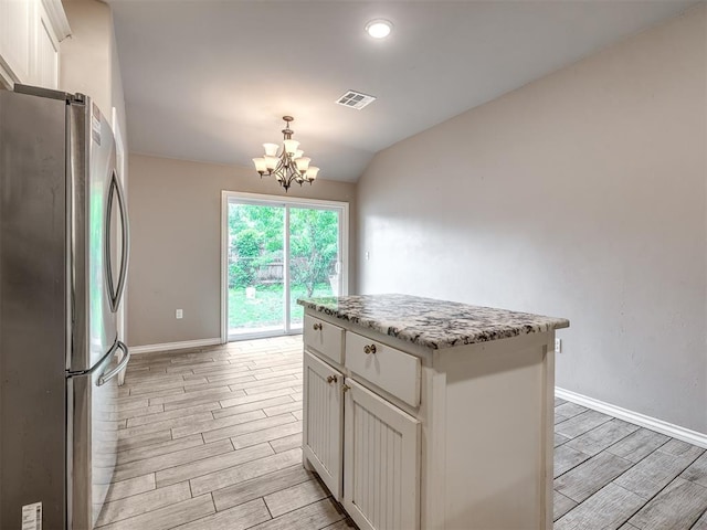kitchen with wood finish floors, a chandelier, freestanding refrigerator, vaulted ceiling, and visible vents