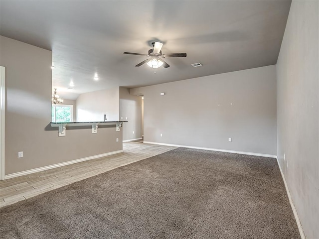 empty room with baseboards, ceiling fan, carpet, and visible vents