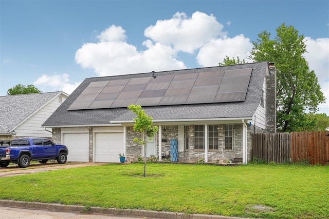 view of front of home with roof with shingles, fence, roof mounted solar panels, a front lawn, and an attached garage