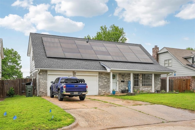 view of front of home featuring a shingled roof, concrete driveway, solar panels, and a front yard
