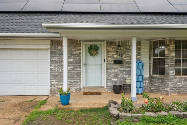 entrance to property with roof with shingles, a porch, and roof mounted solar panels