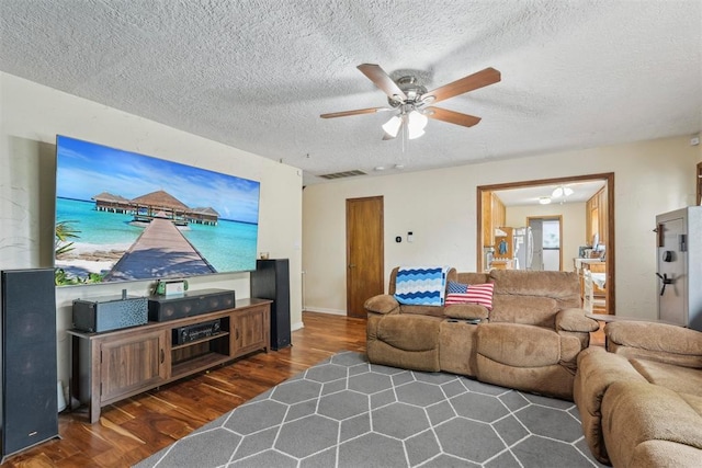 living room with visible vents, a ceiling fan, a textured ceiling, and wood finished floors