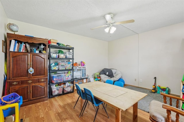 recreation room featuring a ceiling fan, light wood finished floors, and a textured ceiling