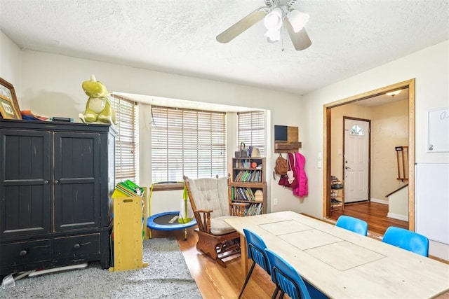 game room with a textured ceiling, ceiling fan, and wood finished floors